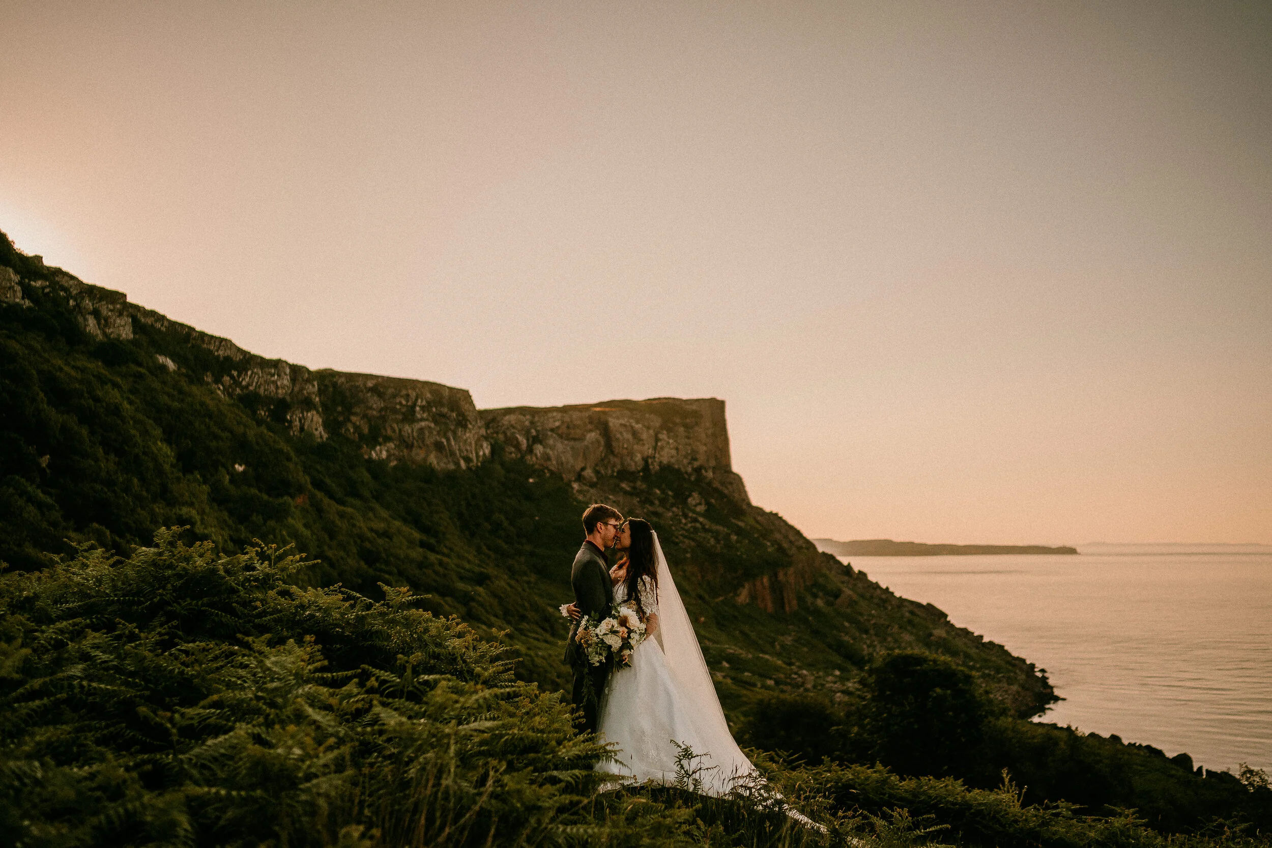 Couple embracing on a dramatic Irish clifftop at sunset